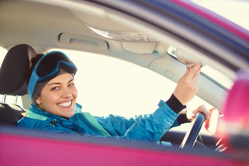 girl driving a car while preparing for skiing on a snowy mountain