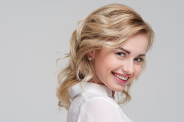 Portrait of curly blonde woman in white shirt.