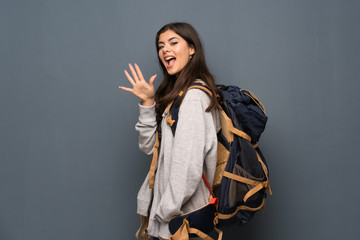 Teenager traveler girl over wall counting five with fingers