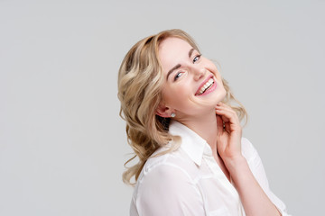 Portrait of smiling curly blonde in white shirt.