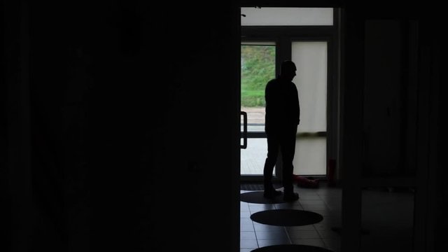Silhouette of middle aged Caucasian male taling on phone with a door in the background.