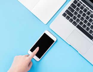 A woman is holding a smartphone isolated with a minimal blue desk, concept of online shopping payment, internet work at home, e-commerce, copy space, flat lay, top view, mock up