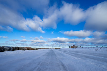Fototapeta na wymiar Beautiful snowy road in winter under blue sky