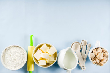 Baking ingredients and tools on trendy bright blue background - flour, eggs, sugar, milk, butter, layout, flatlay top view copy space banner