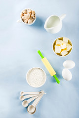 Fototapeta na wymiar Baking ingredients and tools on trendy bright blue background - flour, eggs, sugar, milk, butter, layout, flatlay top view copy space banner