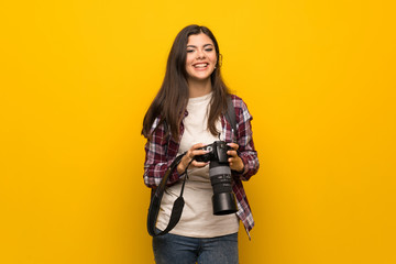 Fototapeta na wymiar Photographer teenager girl over yellow wall