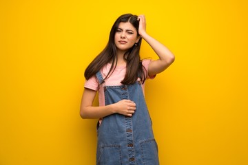 Teenager girl over yellow wall having doubts