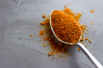Dry red chili pepper in spoon on concrete background with copy space