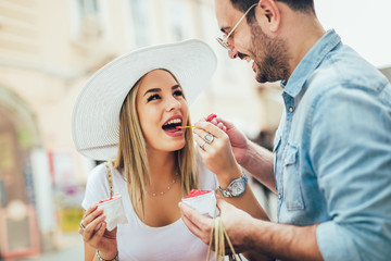 Smiling couple in shopping with ice-cream and shopping bags