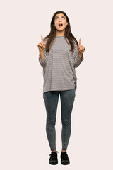 A full-length shot of a Teenager girl with striped shirt pointing up and surprised over isolated background