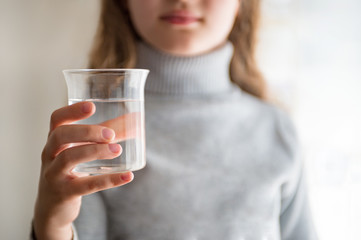 Young woman holding glass with water. Girl drinking water