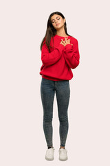 A full-length shot of a Teenager girl with red sweater having a pain in the heart over isolated background
