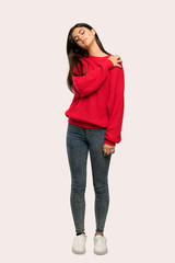 A full-length shot of a Teenager girl with red sweater suffering from pain in shoulder for having made an effort over isolated background