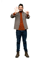 Fototapeta premium Full-length shot of Handsome man with beard counting six with fingers on isolated white background