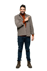 Fototapeta premium Full-length shot of Handsome man with beard pointing to the side to present a product on isolated white background