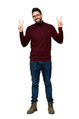 Full-length shot of Handsome man with glasses smiling and showing victory sign with both hands on isolated white background © luismolinero