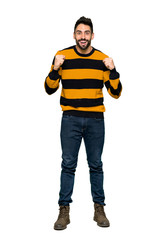 Full-length shot of Handsome man with striped sweater celebrating a victory in winner position on isolated white background