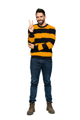 Naklejka premium Full-length shot of Handsome man with striped sweater smiling and showing victory sign on isolated white background