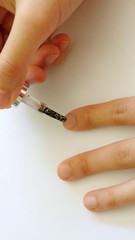 Hand applying glittering nail polish onto finger nail.