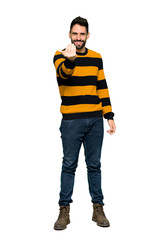 Fototapeta premium Full-length shot of Handsome man with striped sweater inviting to come with hand. Happy that you came on isolated white background