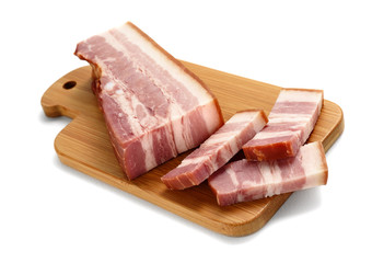 piece of smoked bacon with sliced strips on wooden table isolated