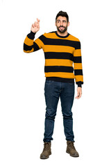 Fototapeta premium Full-length shot of Handsome man with striped sweater with fingers crossing and wishing the best on isolated white background