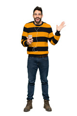 Fototapeta premium Full-length shot of Handsome man with striped sweater surprised and sending a message on isolated white background
