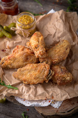 Juicy, crispy chicken wings breaded on wooden background, rustic style.. Fast food 
