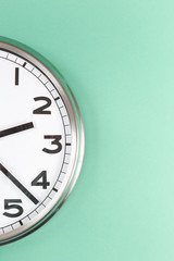 Part of analogue plain wall clock on trendy mint background. Close up with copy space, time...