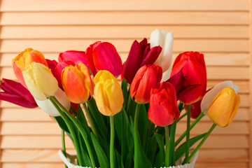tulip flowers are in a basket on the table, wood background