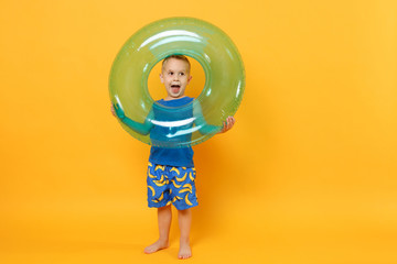 Kid boy 3-4 years old in blue beach summer clothes hold inflatable ring isolated on bright yellow orange wall background children studio portrait. People childhood lifestyle concept Mock up copy space