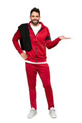 Full-length shot of Handsome sportman holding copyspace imaginary on the palm to insert an ad on isolated white background