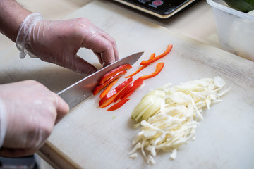 Chef cuts the vegetables into a meal. Preparing dishes. A man uses a knife and cooks.