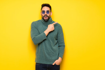 Handsome man with sunglasses pointing to the side to present a product