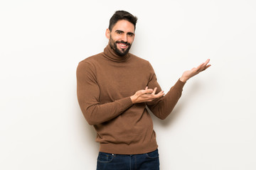 Handsome man over white wall extending hands to the side for inviting to come