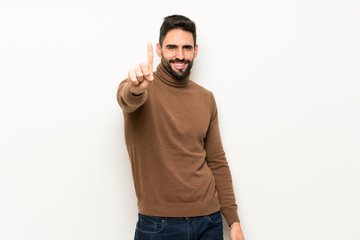 Handsome man over white wall showing and lifting a finger