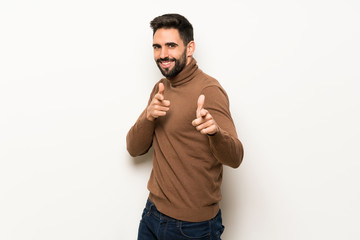 Fototapeta premium Handsome man over white wall pointing to the front and smiling