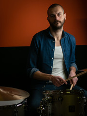 Boy playing drum with jeans shirt and dark background