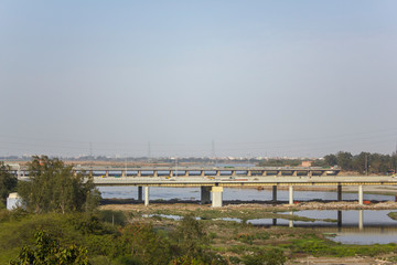 Fototapeta na wymiar bridge over the river Yamuna with car traffic in the background of the city
