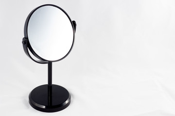 mirror on a black leg stands on a white background