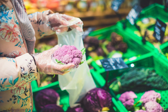 Grocery shopping at supermarket - female hand holding lilac cauliflower - vegan, healthy diet and no gmo food concept