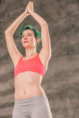 Fototapeta na wymiar Young green-haired woman with nice abs doing yoga pose