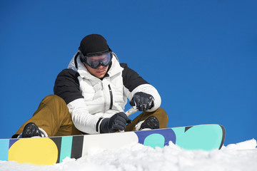 The guy is coming and preparing for skiing with snowboard