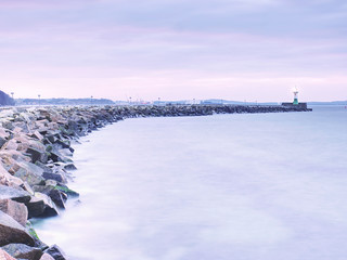 Shinning lighthouse at end of stony pier