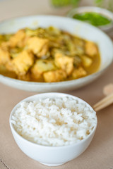 A cup of white rice and a bowl of chicken curry in the background - Japanese cuisine