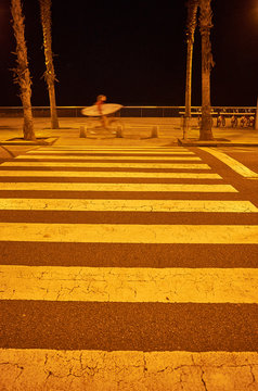 Mann f&auml;hrt mit Fahhrad und Surfboard am Strand vor Zebrasterifen