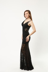 Fototapeta premium Full length photo fashion model woman wearing elegant evening dress black gown posing isolated on white wall background studio portrait. Brunette long hair girl. Mock up copy space. Side profile view.