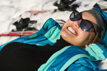 The girl lies in the snow and resting after skiing