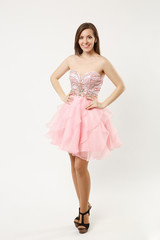 Naklejka premium Full length photo of fashion model woman wearing elegant evening dress gown posing isolated on white wall background studio portrait. Brunette long hair girl. Mock up copy space. Pink dress face view.