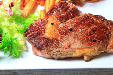 plate of steak with french fries and lettuce salad